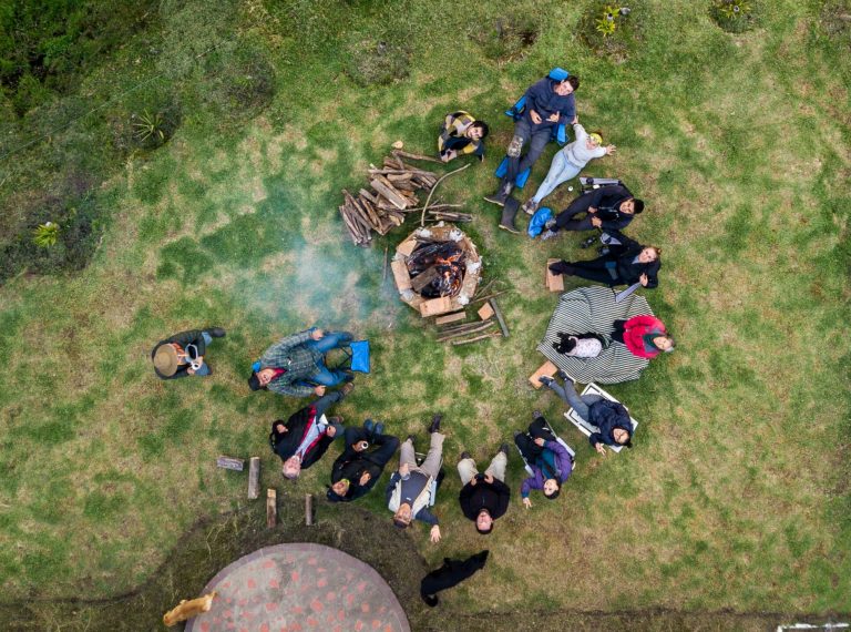An aerial view of a group of people surrounding the fire pit at the campsite